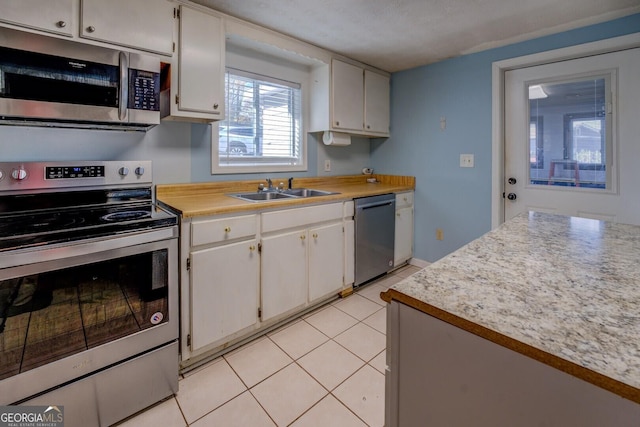 kitchen with light tile patterned floors, appliances with stainless steel finishes, sink, and white cabinets