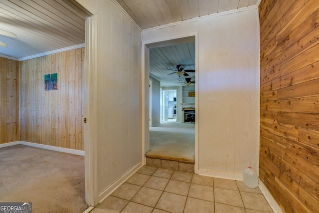 hallway with ornamental molding and wood walls