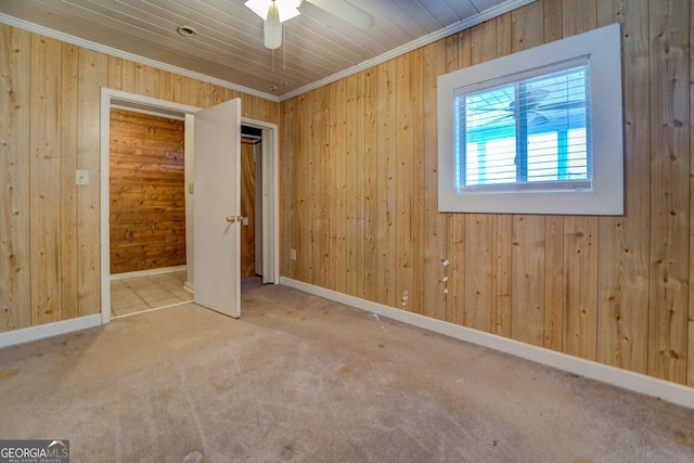 unfurnished bedroom with ornamental molding, carpet, ceiling fan, and wooden walls