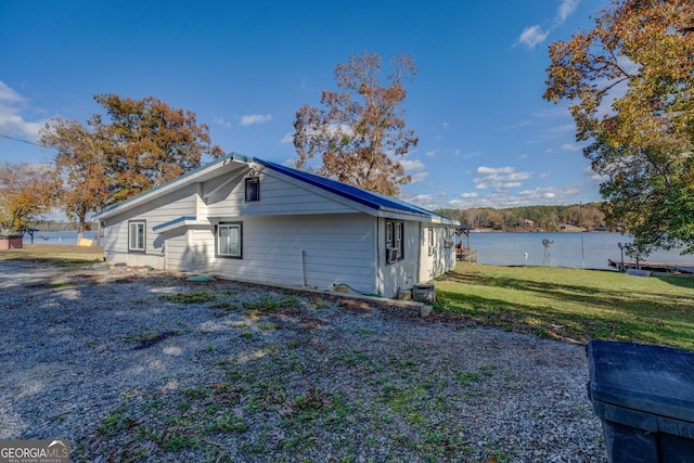 view of side of home featuring a lawn and a water view