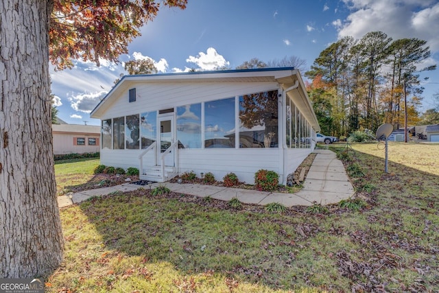 view of front facade featuring a front lawn and a sunroom