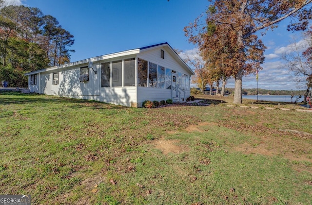 view of side of property with a yard, a sunroom, and a water view