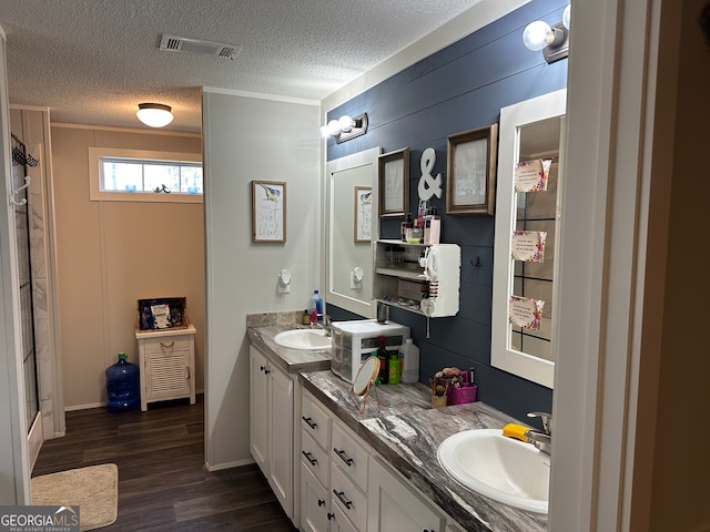 bathroom featuring crown molding, hardwood / wood-style floors, vanity, and a textured ceiling