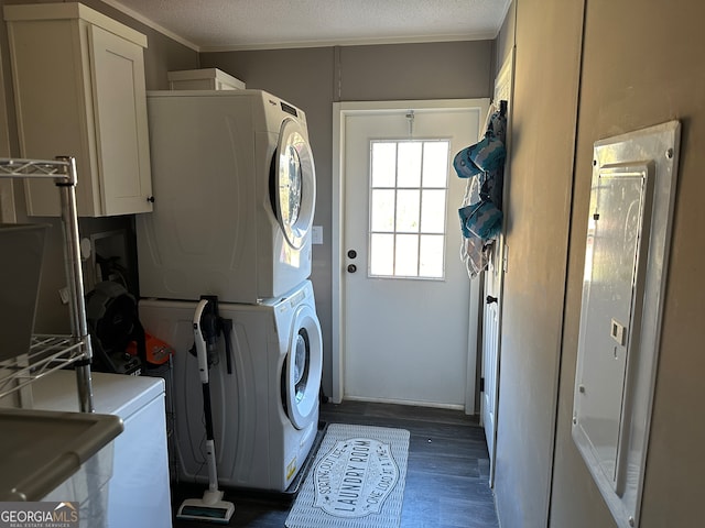 clothes washing area featuring cabinets, stacked washer and clothes dryer, crown molding, a textured ceiling, and dark hardwood / wood-style flooring