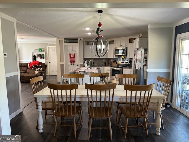 dining space with sink, a textured ceiling, dark wood-type flooring, and a notable chandelier