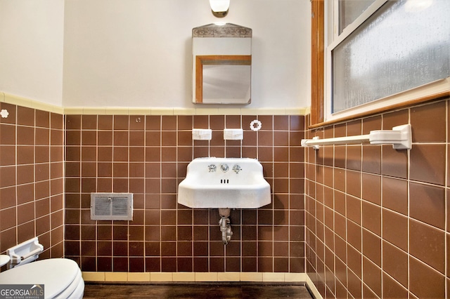 bathroom featuring wood-type flooring, toilet, tile walls, and sink