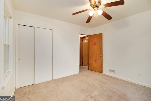 unfurnished bedroom with ceiling fan, a closet, and light colored carpet