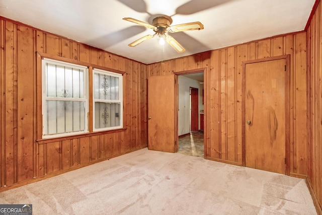 spare room featuring ceiling fan, light colored carpet, crown molding, and wooden walls