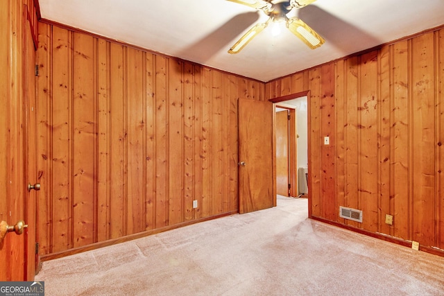 carpeted empty room featuring radiator heating unit, crown molding, ceiling fan, and wooden walls