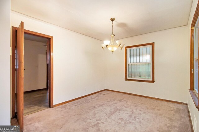 empty room with carpet flooring and an inviting chandelier