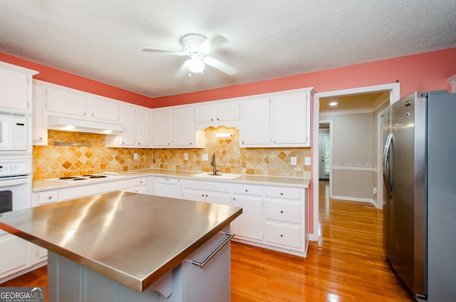 kitchen with white appliances, white cabinets, sink, light wood-type flooring, and a kitchen island