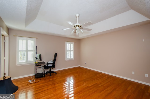 office featuring ceiling fan, a raised ceiling, wood-type flooring, and a textured ceiling