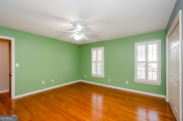 unfurnished bedroom with hardwood / wood-style floors, a textured ceiling, and ceiling fan