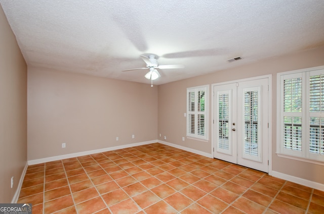 tiled empty room featuring ceiling fan, french doors, and a textured ceiling