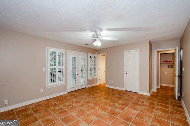 spare room with ceiling fan, light tile patterned flooring, and a textured ceiling