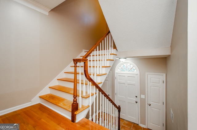 stairway with crown molding and hardwood / wood-style floors