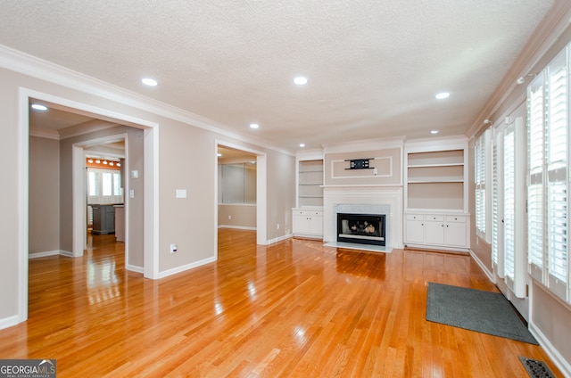 unfurnished living room with plenty of natural light, a fireplace, wood-type flooring, and a textured ceiling