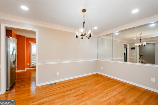 unfurnished room with a chandelier, crown molding, and wood-type flooring