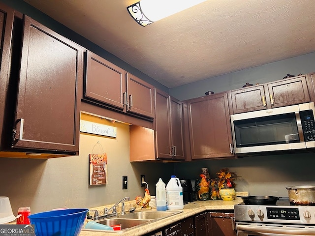 kitchen with sink, dark brown cabinets, a textured ceiling, and range