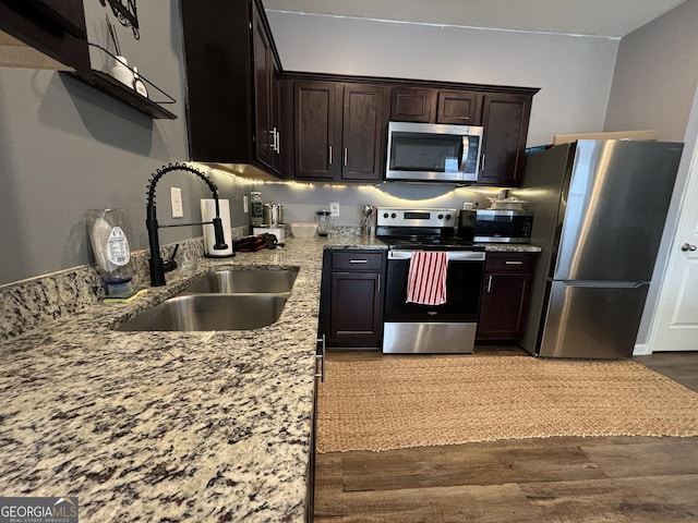 kitchen featuring stainless steel appliances, wood-type flooring, sink, and dark brown cabinetry