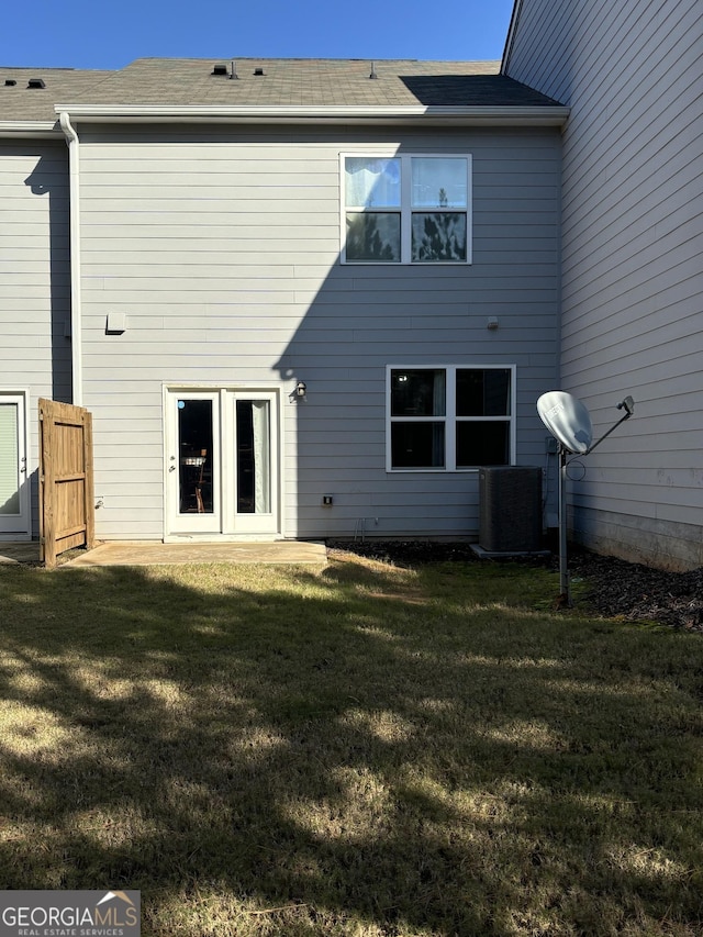 back of property featuring central air condition unit and a lawn