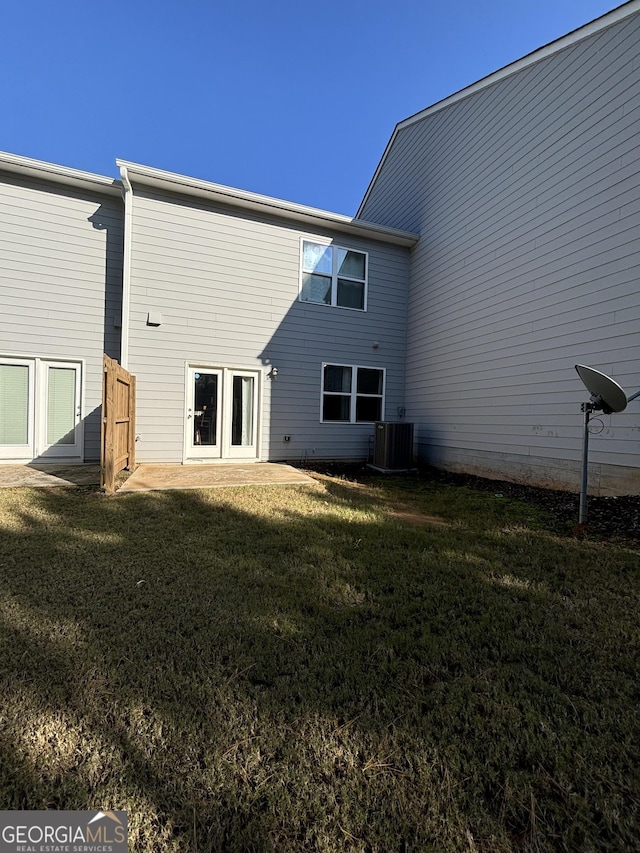 back of property featuring central AC and a lawn