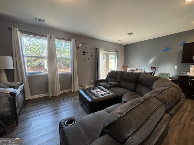 living room featuring dark wood-type flooring and a healthy amount of sunlight