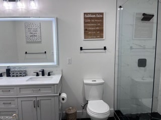 bathroom featuring a tile shower, vanity, and toilet