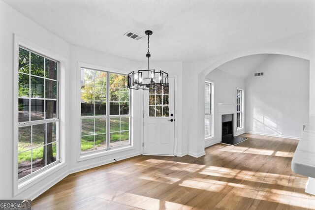 unfurnished dining area with a chandelier, wood-type flooring, and a wealth of natural light