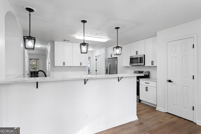 kitchen featuring kitchen peninsula, white cabinetry, and appliances with stainless steel finishes