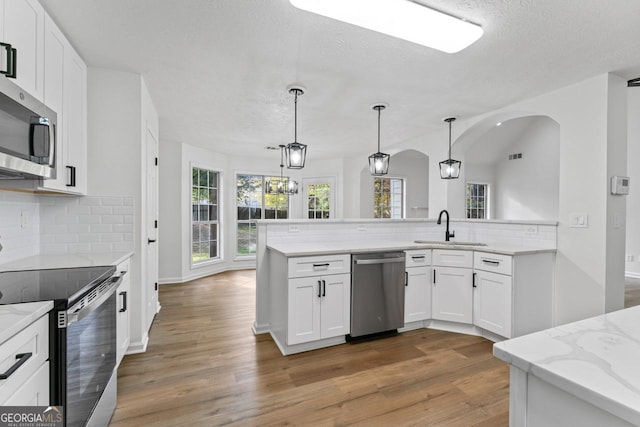 kitchen featuring white cabinets, appliances with stainless steel finishes, decorative light fixtures, and sink