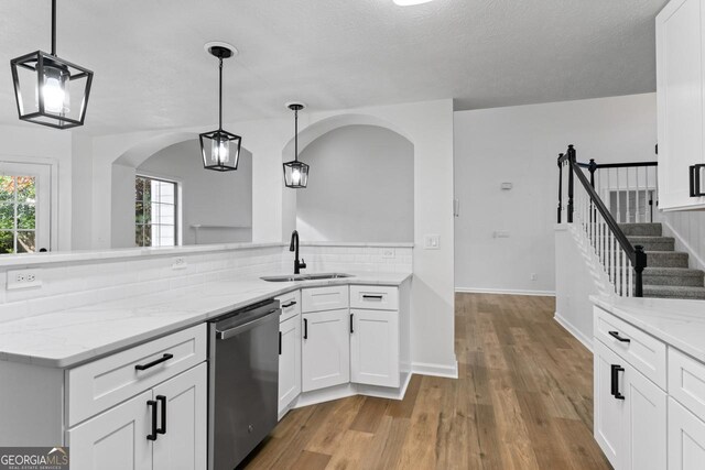 kitchen with dishwasher, white cabinetry, hanging light fixtures, and sink