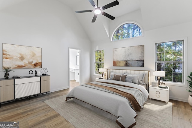 bedroom featuring ceiling fan, high vaulted ceiling, connected bathroom, and hardwood / wood-style floors