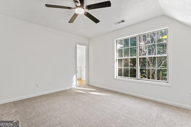 empty room with a textured ceiling, carpet floors, vaulted ceiling, and ceiling fan