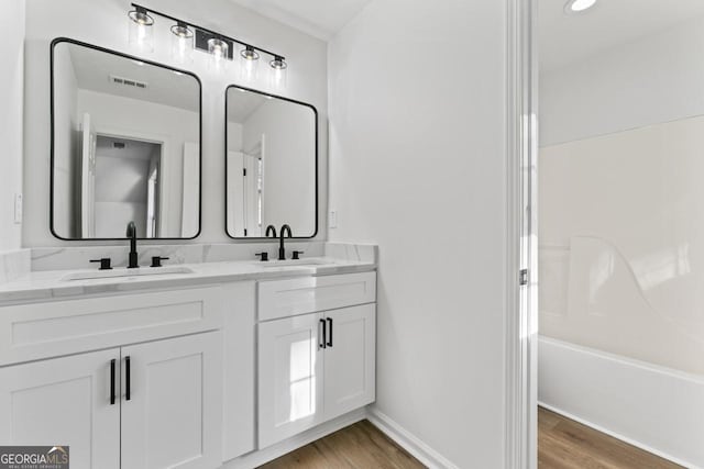 bathroom featuring hardwood / wood-style flooring, vanity, and bathtub / shower combination