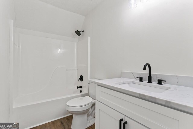 full bathroom featuring vanity, hardwood / wood-style flooring, toilet, and shower / washtub combination