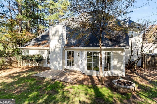 rear view of property featuring a patio, an outdoor fire pit, and a lawn