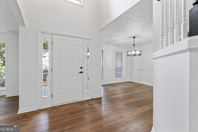 foyer entrance featuring a chandelier, a textured ceiling, and dark hardwood / wood-style floors