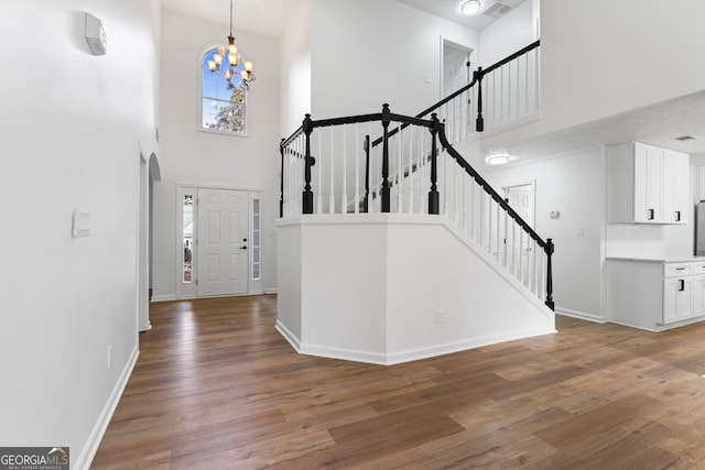 foyer featuring hardwood / wood-style floors, a notable chandelier, and a towering ceiling