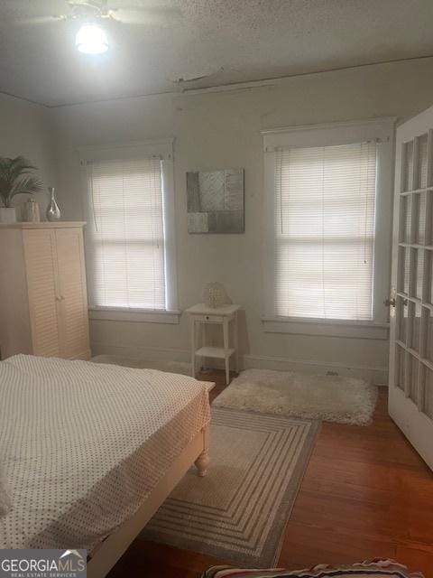 bedroom with multiple windows, hardwood / wood-style floors, and a textured ceiling