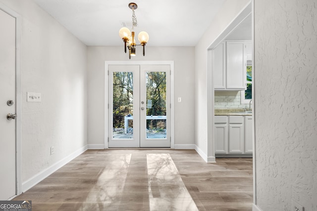 entryway with sink, french doors, a chandelier, and light wood-type flooring