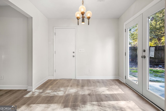 interior space featuring french doors, light hardwood / wood-style floors, and a notable chandelier