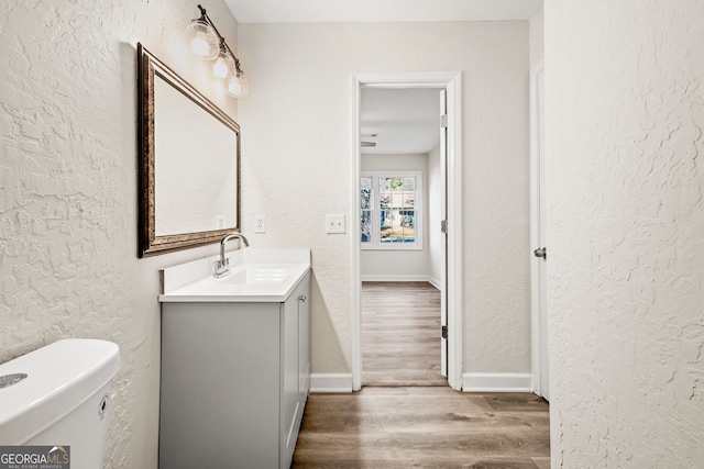 bathroom with hardwood / wood-style floors, vanity, and toilet