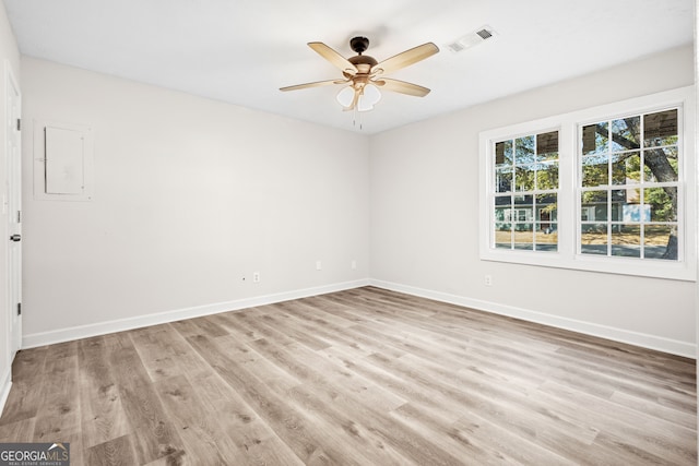 spare room featuring electric panel, ceiling fan, and light hardwood / wood-style flooring