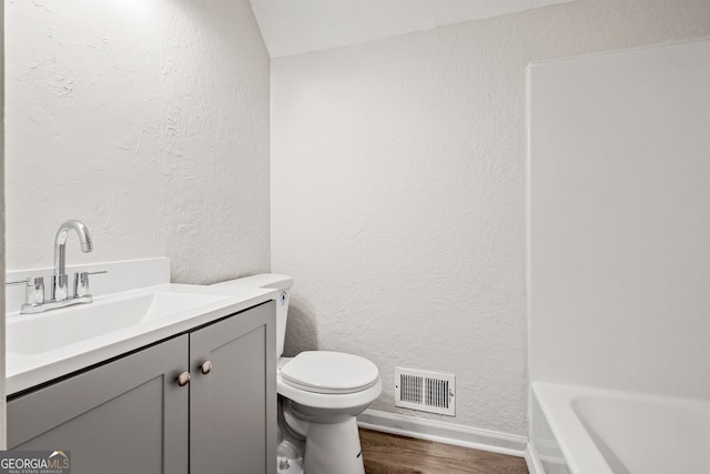 bathroom featuring a washtub, toilet, vanity, and hardwood / wood-style flooring