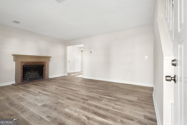 unfurnished living room with a brick fireplace and light hardwood / wood-style flooring