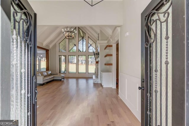 foyer entrance with a chandelier, light wood-type flooring, and lofted ceiling with beams