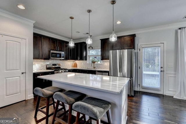 kitchen with decorative light fixtures, a center island, dark hardwood / wood-style floors, and appliances with stainless steel finishes