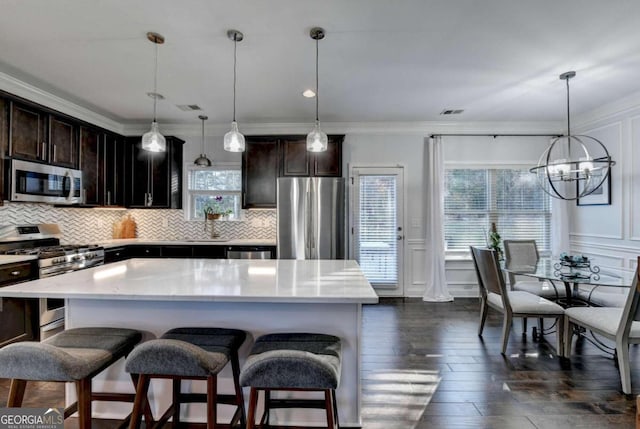 kitchen with a center island, stainless steel appliances, dark hardwood / wood-style floors, pendant lighting, and a breakfast bar