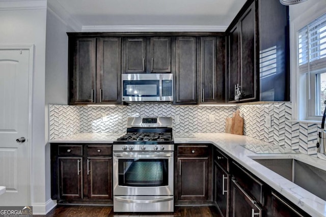 kitchen with light stone countertops, appliances with stainless steel finishes, backsplash, dark brown cabinets, and dark hardwood / wood-style floors